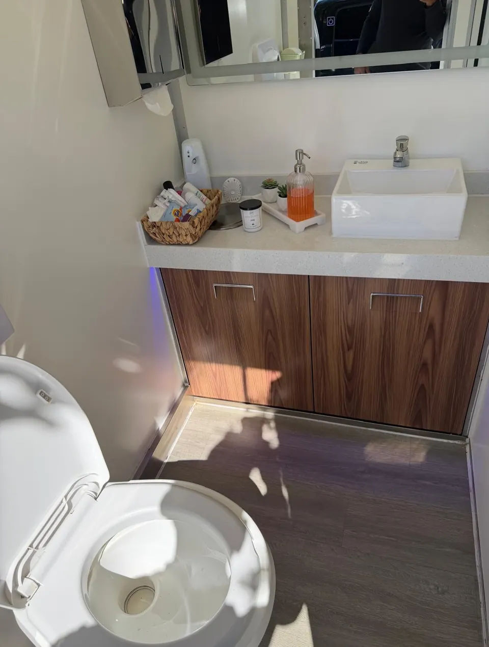 Wood-finish vanity and toilet inside a restroom trailer