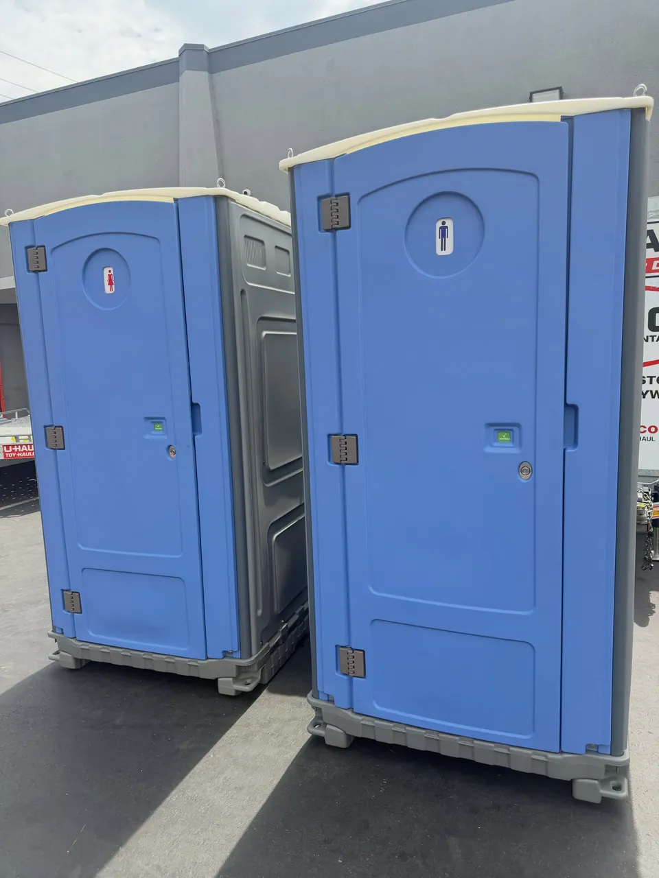 Two blue portable toilets on a paved surface